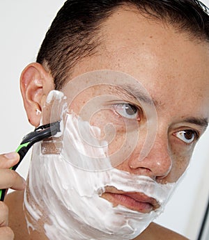 Portrait of a young man shaving his beard