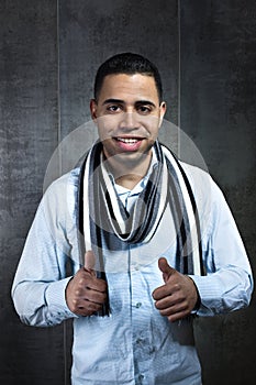 Portrait of a young man showing thumbs up in dark wall