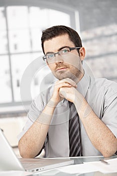 Portrait of young man sitting at desk using laptop