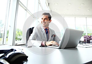 Portrait of young man sitting at his desk in the office