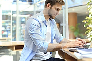 Portrait of young man sitting at his desk in the office