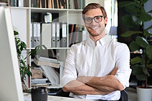 Portrait of young man sitting at his desk in the office.