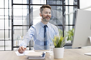 Portrait of young man sitting at his desk in the office.