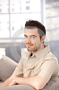 Portrait of young man sitting on sofa smiling