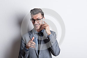 Portrait of a young man with smartphone in a studio, making a phone call.