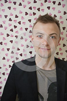 Portrait of young man smiling over heart shaped wallpaper