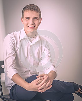 Portrait of young man smiling sitting on gray background