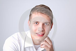 Portrait of young man smiling sitting on gray background. Portrait of young man