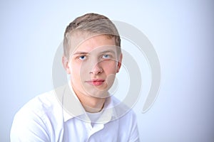 Portrait of young man smiling sitting on gray background. Portrait of young man