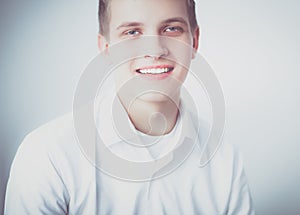 Portrait of young man smiling sitting on gray background. Portrait of young man