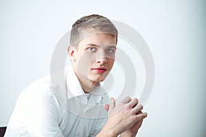 Portrait of young man smiling sitting on gray background. Portrait of young man