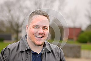 Portrait of a young man standing outside in a park in spring and looking friendly to side