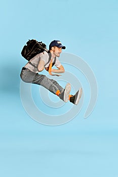 Portrait of young man, student in casual clothes posing isolated over blue background. Juming in a good mood