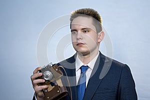 Portrait of a young man in a suit with an old camera, perhaps he is a novice journalist doing a report, a diplomat or secret
