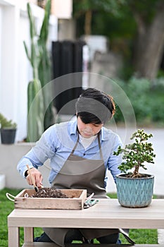 Portrait of young man taking care of plants at back garden.