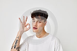 portrait of a young man tattoo on hands in white t-shirt light background unaltered