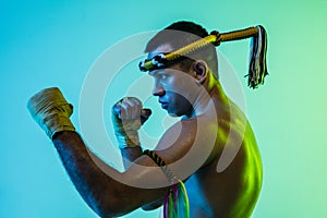 Portrait of young man thai boxer training over blue background.