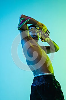 Portrait of young man thai boxer training over blue background.