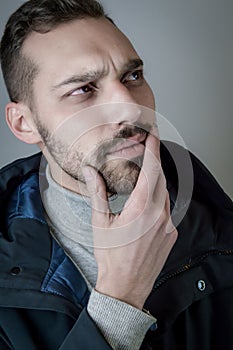 Portrait of a young man touching his chin in a moment of doubt or reflection