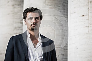 Portrait of young man with trendy style. Trendy hair and goatee. He wears a white shirt and jacket