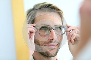 Portrait of young man trying on eyeglasses