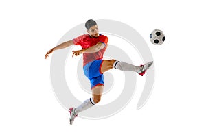 Portrait of young man in uniform, professional football player kicking ball in a jump isolated over white studio