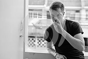 Portrait of young man using asthma inhaler at home