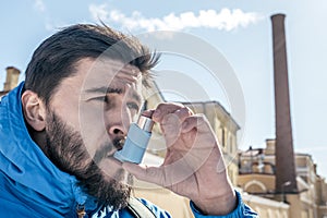 Portrait of young man using asthma inhaler outdoor