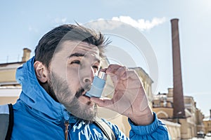 Portrait of young man using asthma inhaler outdoor