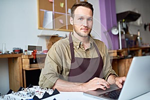 Young Man Using Laptop in Jewelry Workshop