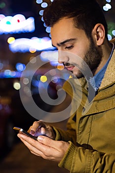 Portrait of young man using his mobile phone on the street at ni