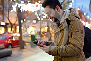 Portrait of young man using his mobile phone on the street at ni