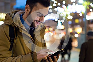 Portrait of young man using his mobile phone on the street at ni