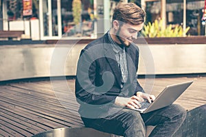 Portrait of young man using a laptop outdoor