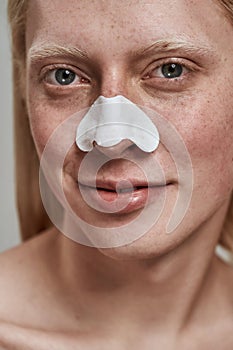 Portrait of young man using nose pore cleansing strips