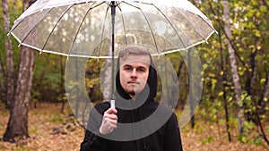 Portrait of a young man walking along the autumn park in a rainy day