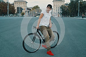 Portrait of young man walking with thoughtfully classic bicycle