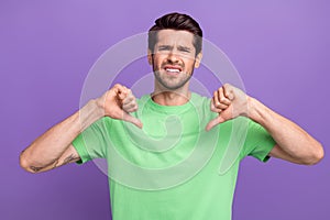 Portrait of young man wear trendy green t-shirt direct fingers himself dissatisfied dislike thumbs down isolated on