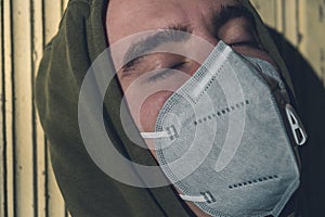 young man wearing a FFP3 corona mask with his eyes closed in the sun photo