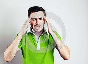 Portrait of young man wearing green shirt having head pain