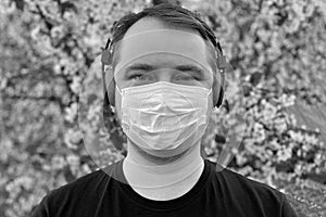Portrait of young man, wearing the medical flu mask, on flower background