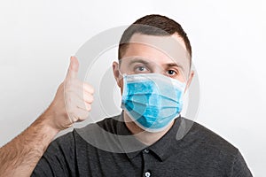 Portrait of young man wearing a medical mask at white background. Person is happy because he is finally healthy. Coronavirus