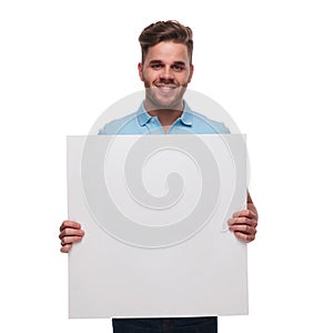 Portrait of young man wearing polo shirt holding blank sign