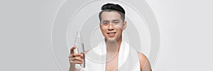 Portrait of young man with a white towel on his shoulder holding a water bottle  on white background