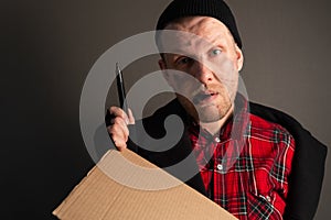 Portrait a young man who holds a felttip pen in his mouth to write text on cardboard. begging concept photo