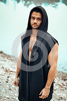 Portrait of a young man who stands with a bare torso on a lake background