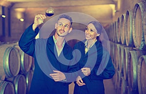 Portrait of young man and woman holding glass of wine in winery