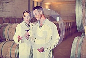 Portrait of young man and woman holding glass of wine in winery