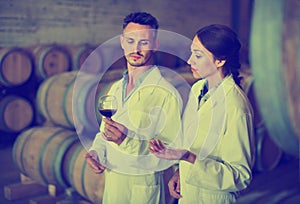 Portrait of young man and woman holding glass of wine in winery