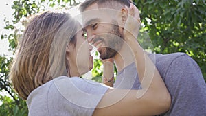 Portrait of young man and woman kissing and hugging in sun light in the summer garden. Happy young family resting